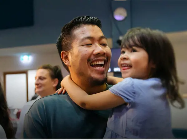 Two parents hold their young children as they all sing during a Sunday service.