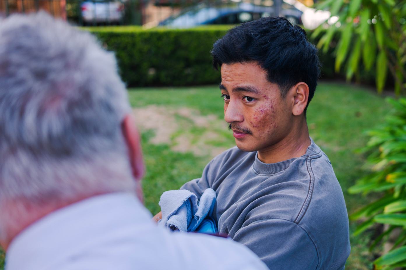 A young man talks with a Salvos officer in a park.