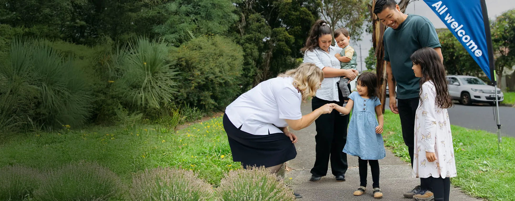 A Salvation Army officer warmly greeting a family of five on a path.