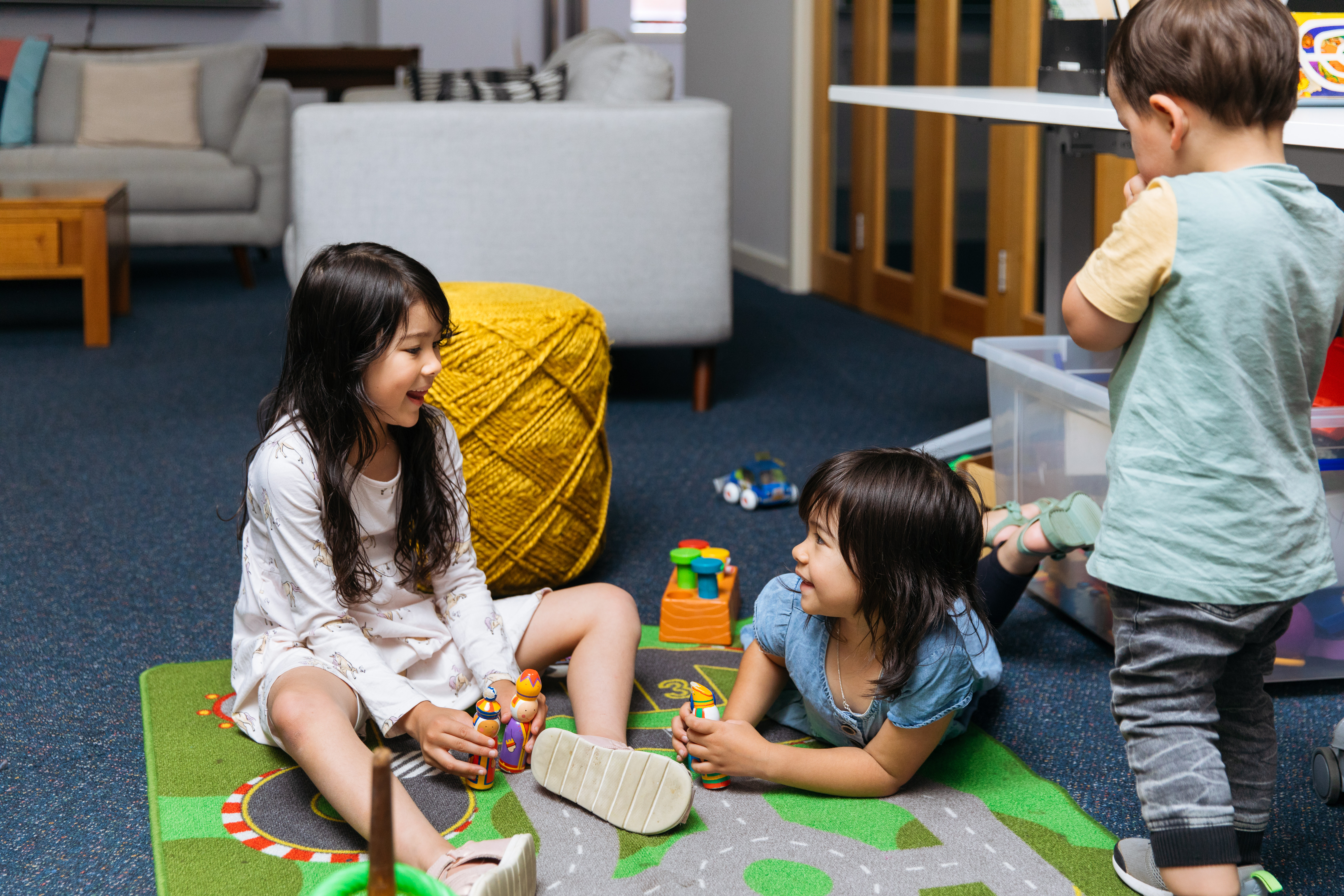 Three children similing as they play on a playmat. 
