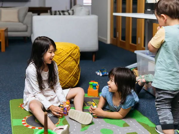Three children similing as they play on a playmat.