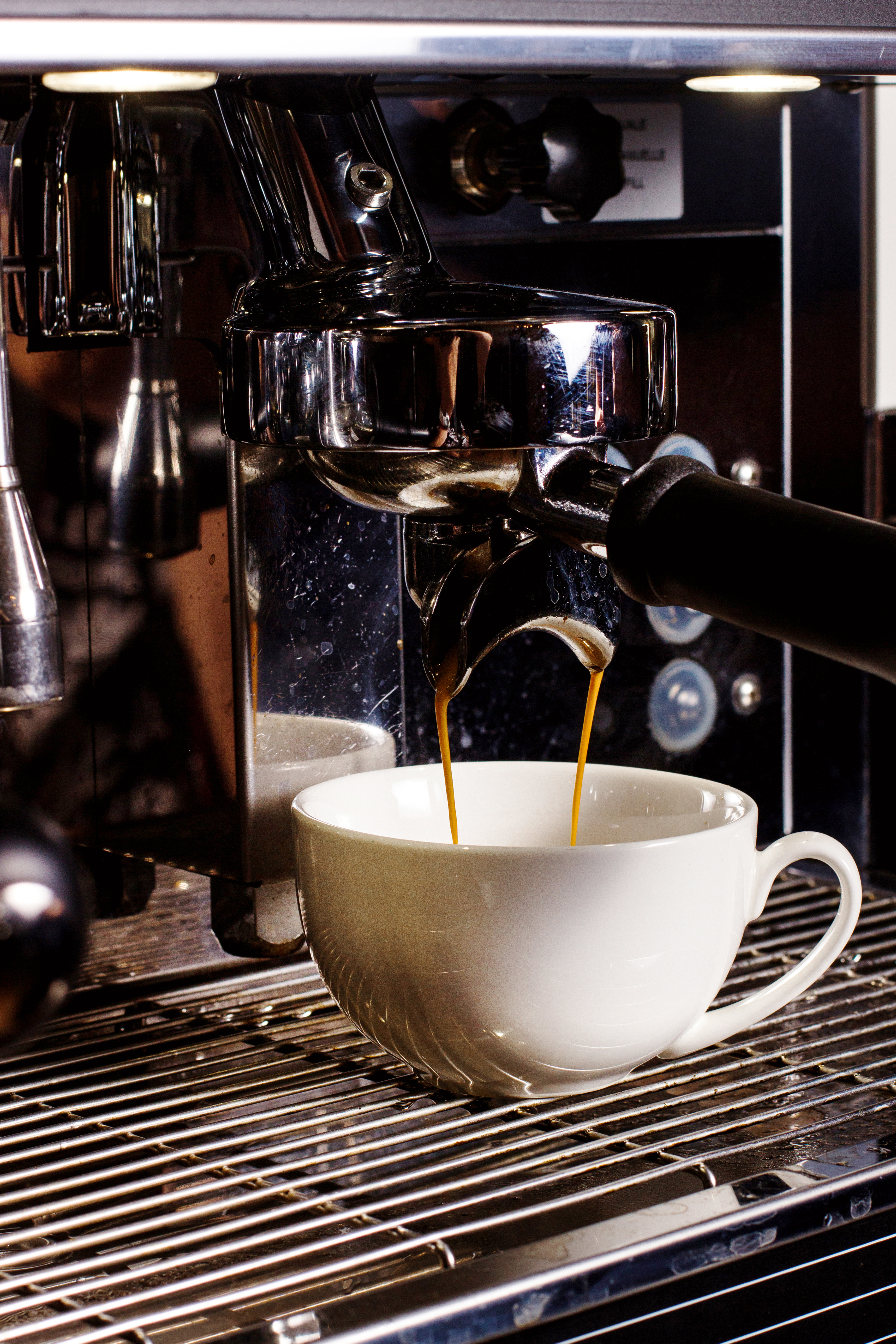 Coffee being poured from a coffee machine into a cup.