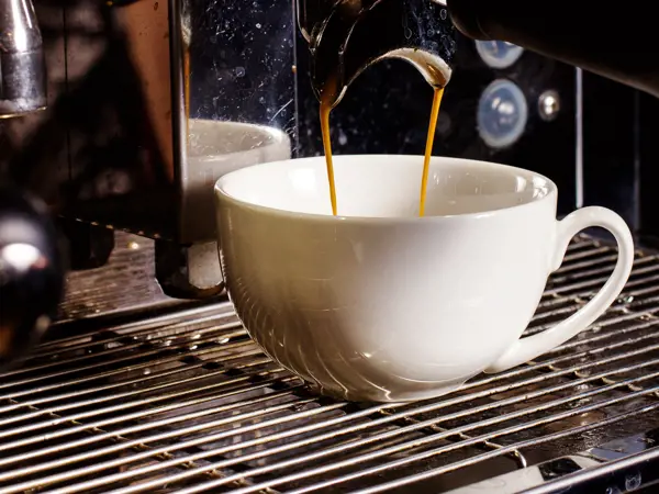 Coffee being poured from a coffee machine into a cup.