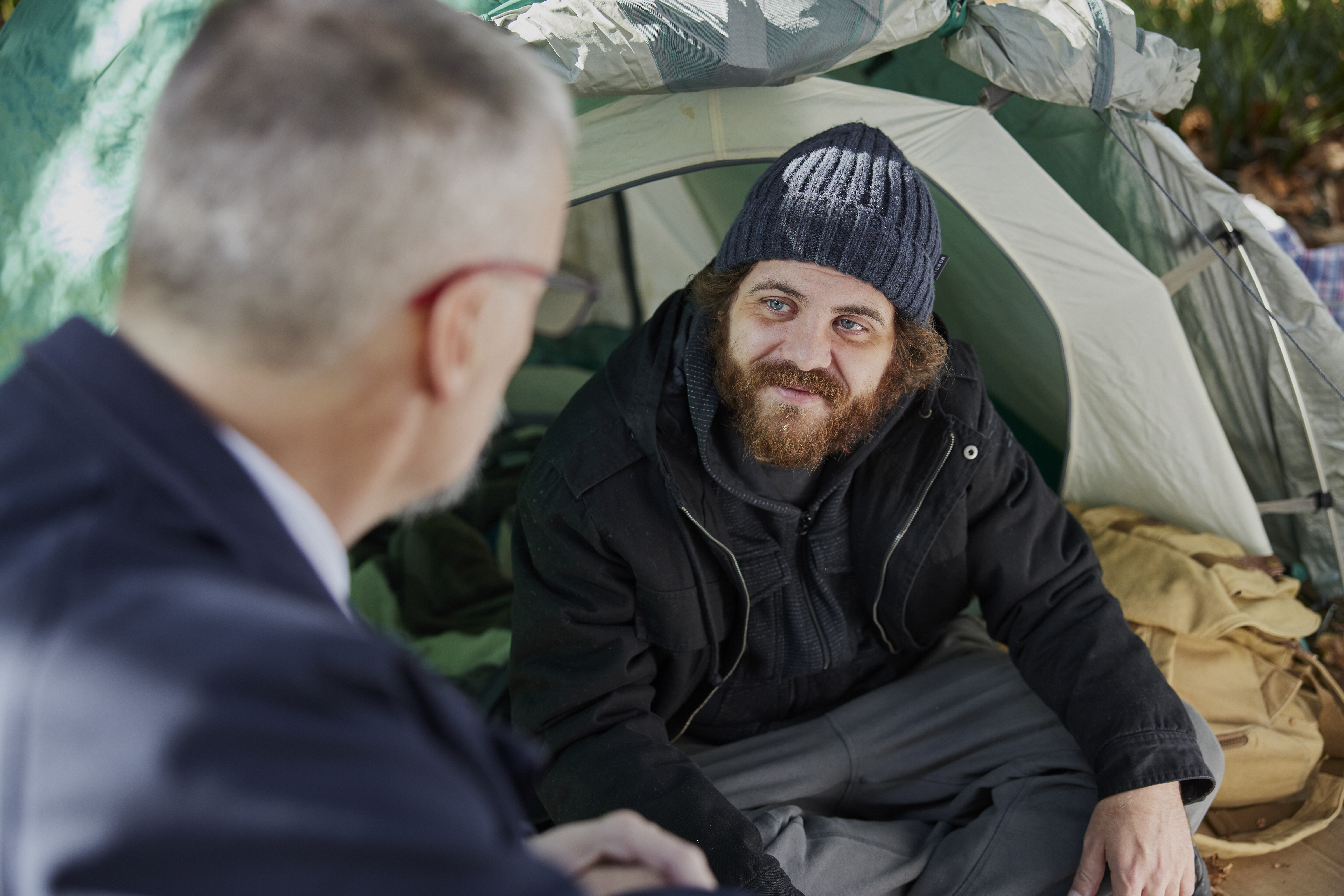 A Salvos officer talks with a young man living in a tent