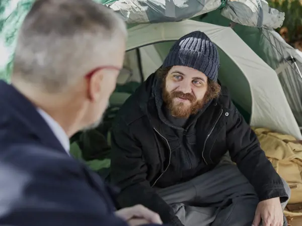 A Salvos officer talks with a young man living in a tent