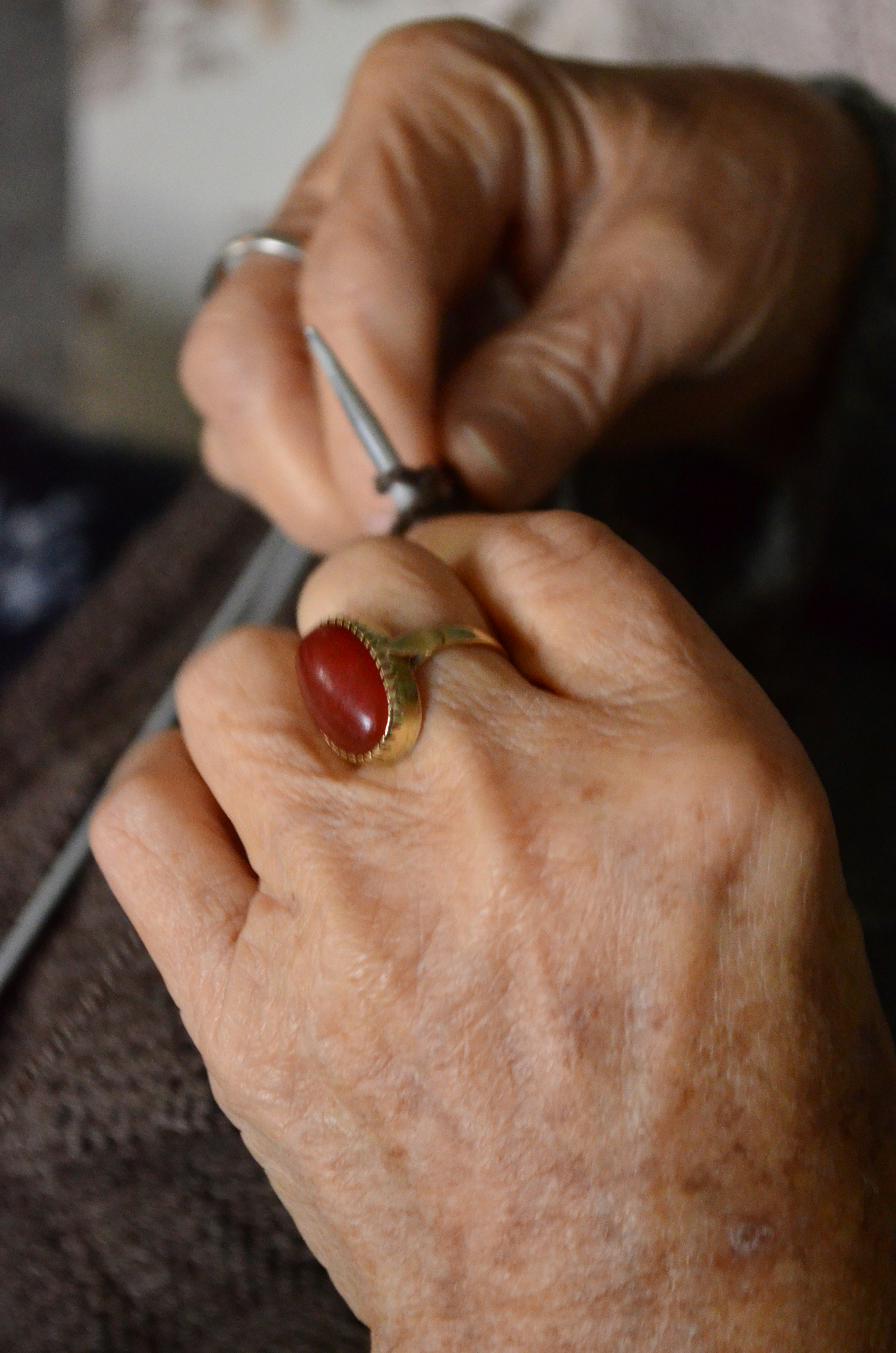 Person knitting with a ruby ring on their finger.