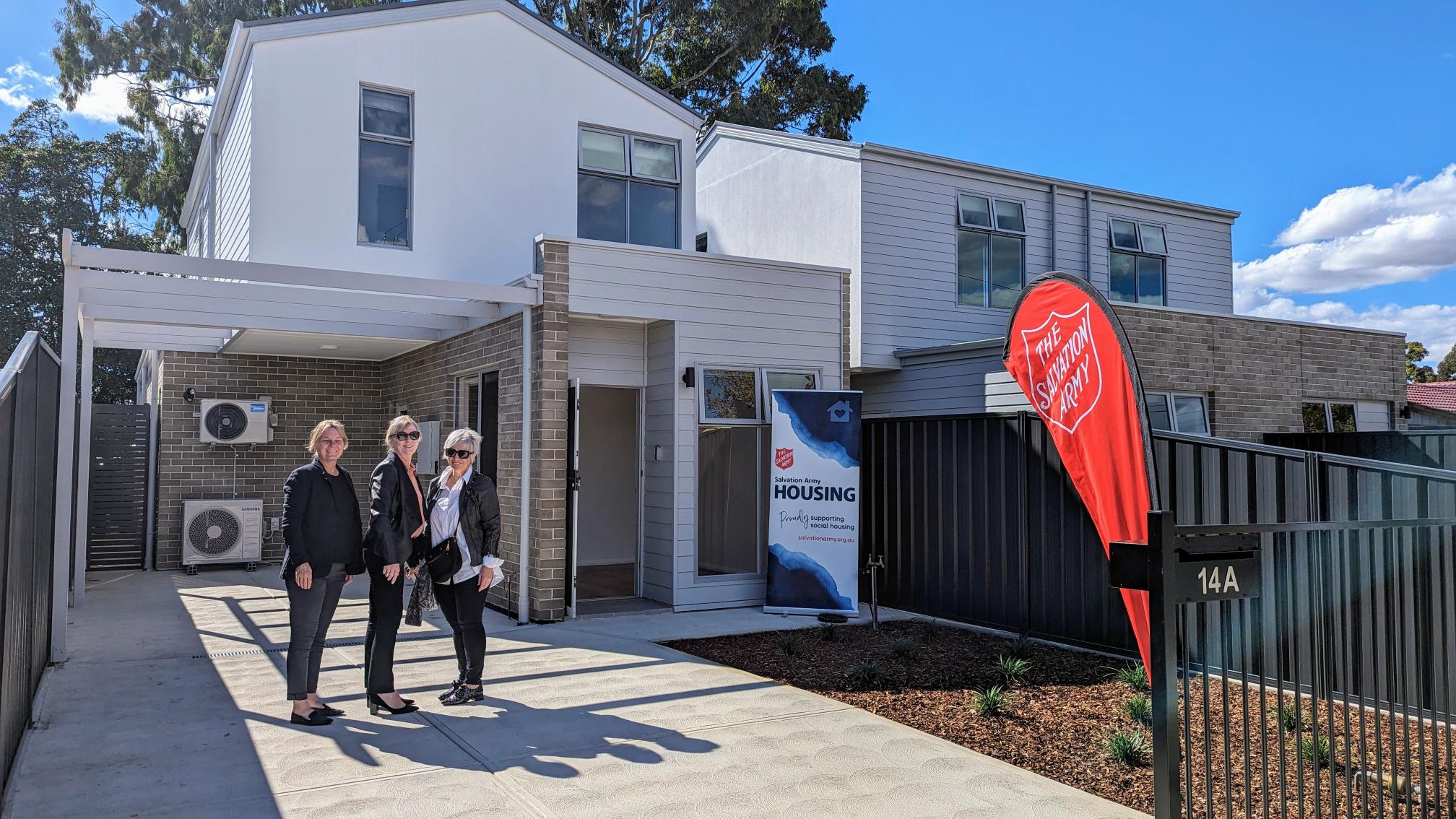 Three people standing in front of Ingle farm housing SA