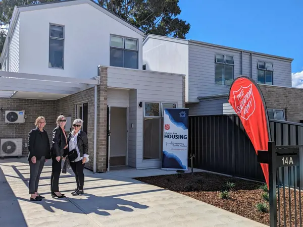 Three people standing in front of Ingle farm housing SA