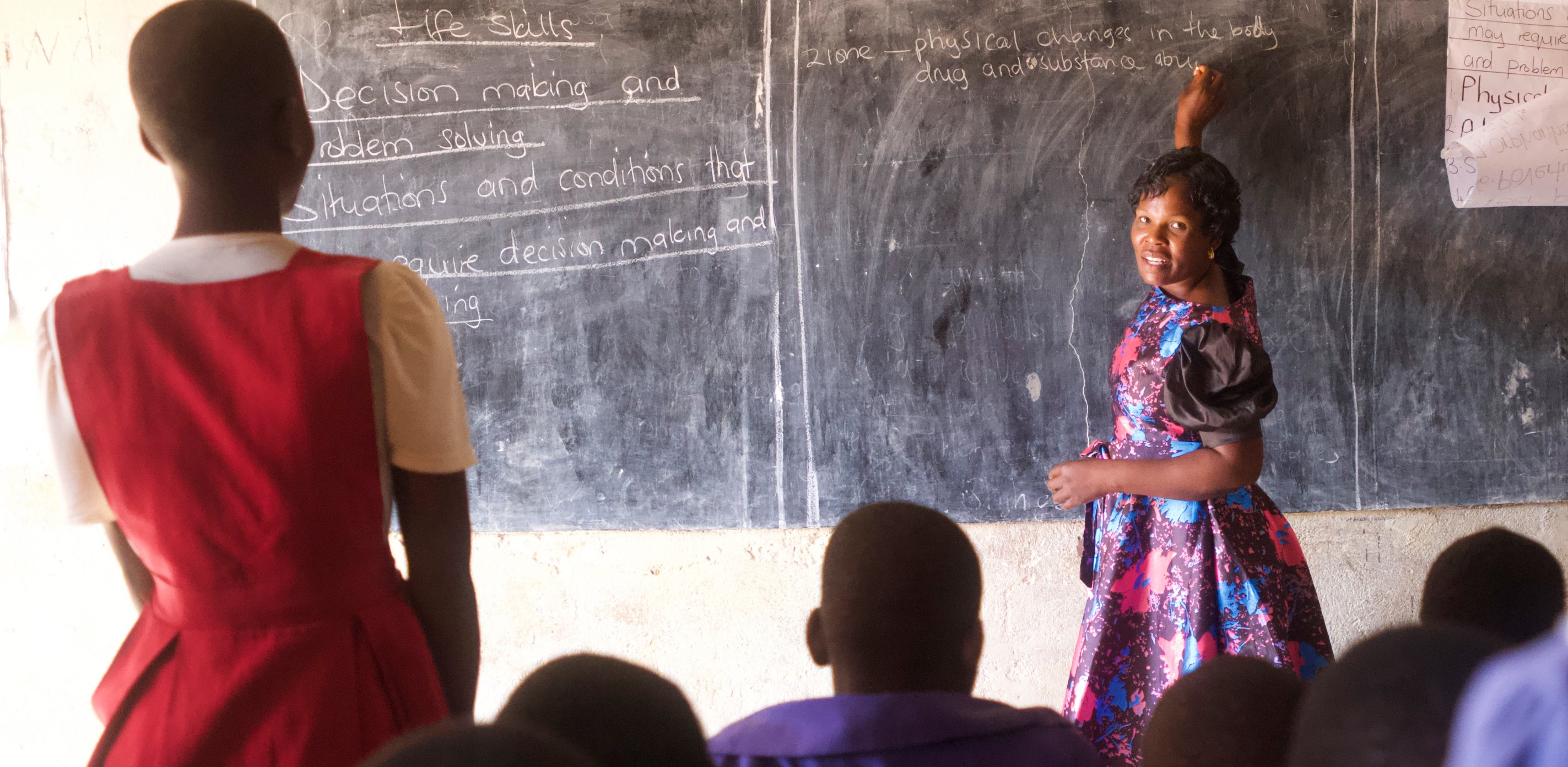 A colorfully dressed teacher directs her students